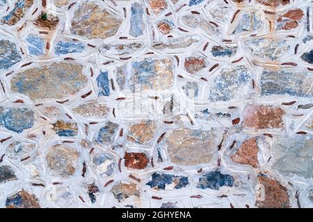 Background texture of wall made of colored stones with white putty.  Stock Photo