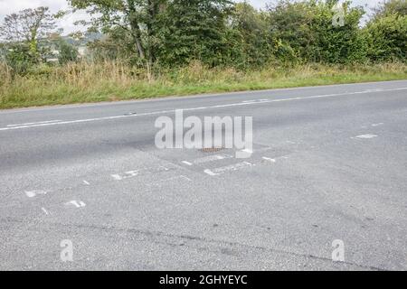 Poorly maintained white road markings at the T-junction of a country A road. For road safety, fading away metaphor, difficult to see. Stock Photo