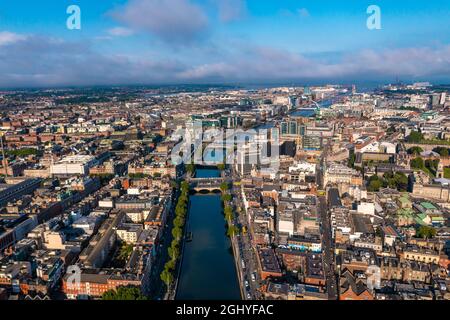 Establisher shot of Dublin skyline with river flowing with bridge connecting two sides of street surrounded by buildings during a cloudy day Stock Photo