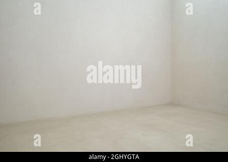 Empty interior white polished concrete room. Vacant inner space at corner of the white rough wall and floor. Stock Photo