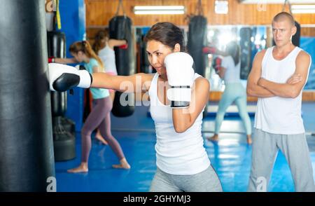 Asian female practicing punches with boxing bag at gym Stock Photo