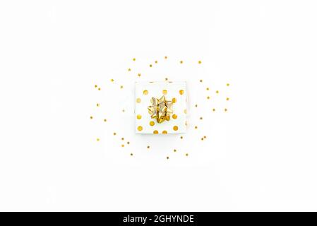 Top view of a golden dotted gift box and star shaped golden sequins on a white background. Stock Photo
