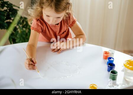 Young cute girl spending a time drawing using online lessons on laptop. Distance learning, online education. Stock Photo
