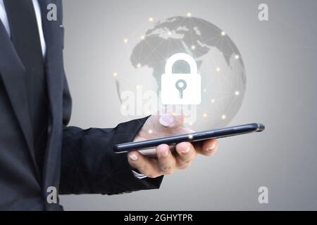 Businessman holding mobile phone with shield lock. Cyber security data protection and information technology network concept. Stock Photo