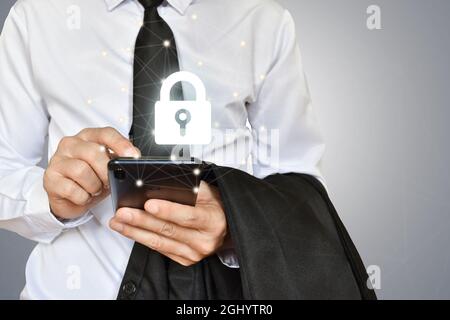 Businessman holding mobile phone with shield lock. Cyber security data protection and information technology network concept. Stock Photo