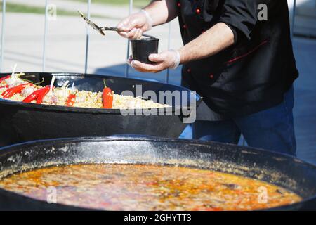 The cook cooks food outside in large vats on coals in the open air Stock Photo