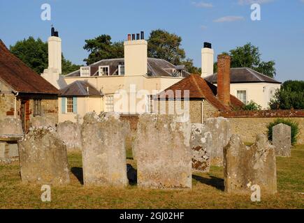 Gravestones in graveyard of Church of St Mary the Virgin and period house soon before sunset in West Malling, Kent, England Stock Photo