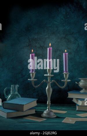 Magic and divination. Candles and old books, magic potion, divination cards. Toned image Stock Photo
