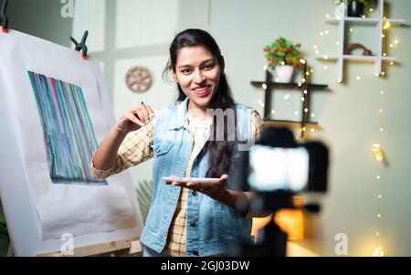 Young girl artist teaching canvas painting by recording on camera - concept of online teaching, virtual class or education during coronavirus, covid Stock Photo