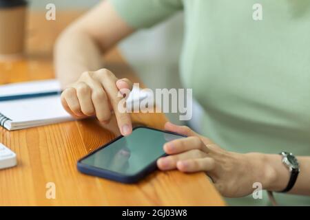 Woman's hands using mobile phone on work table at home, businesswoman searching information via smartphone, close up Stock Photo
