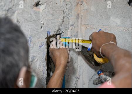 Worker man with measuring tape measuring water pipe on concrete wall for renovate bathroom Stock Photo