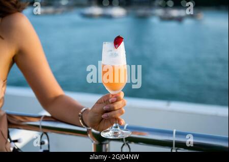 Woman hand holding mixed berry cocktail on rooftop restaurant at the sea Stock Photo