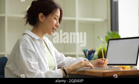 Young female architects or interior designers working in the office, taking notes, using laptop, planning project, laptop blank screen mockup Stock Photo