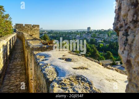 View of the Ramparts Walk, over the old city walls, and the Yemin Moshe neighborhood in the new city, with its windmill, in Jerusalem, Israel Stock Photo