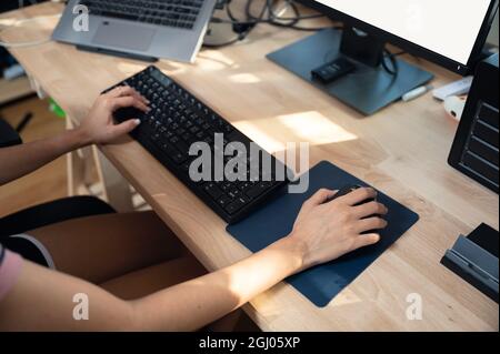 Female freelancer working with computer, typing keyboard and clicking mouse on wooden desk. work from home concept Stock Photo