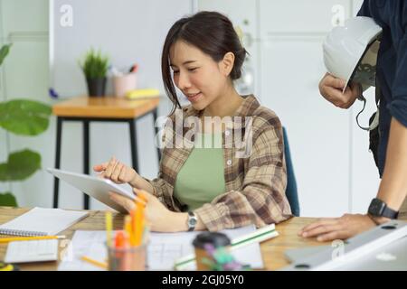 Asian female engineer discussing with co-worker at office, using digital tablet, engineer architect workspace Stock Photo