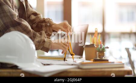 Engineers office project, Closeup, engineer architecture using divider compass to measuring building scale on blueprint, equipment architects Stock Photo