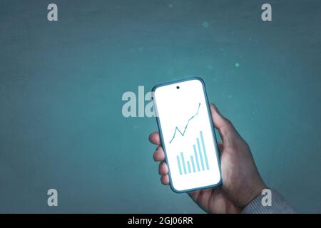 Hand holding a glowing smartphone with chart graphics Stock Photo