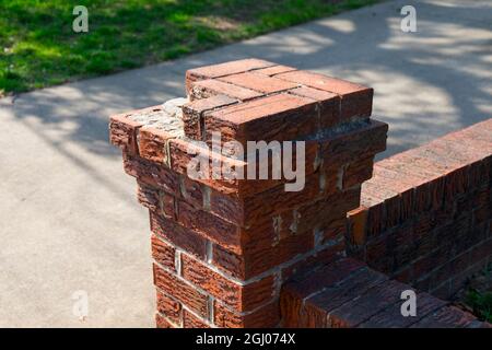 A corner column of a brick wall surrounding a house, missing a few bricks and needing repair. In Arlington, Virginia. Stock Photo