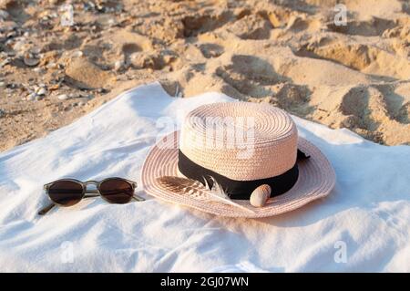 Summer set with a hat and sunglasses on the beach by the sea at a sunrise. Ready to summer. Stock Photo