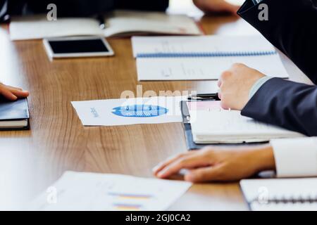 Close-up of business people in meeting session with data papers and notebook on table Stock Photo