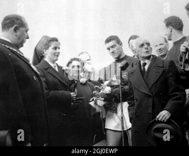 Manchester United chairman Harold Hardman speaks into the microphone while the team skipper Bill Foulkes stands by to present a bouquet of red and white carnations to the wife of Professor Goerg Maurer, the senior surgeon of the Rechts Der Isar Hospital in Munich.The ceremony took place at Manchester United, when the party of thirty one doctors and nurses who tended the injured in the air crash, were thanked publicly and given a rousing reception by fans. 9th March 1958. Stock Photo