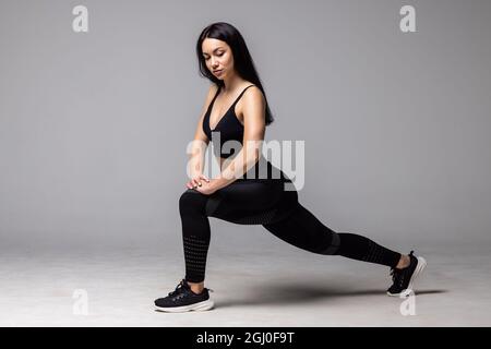 Athletic young woman doing lower body sport exercise, stretching