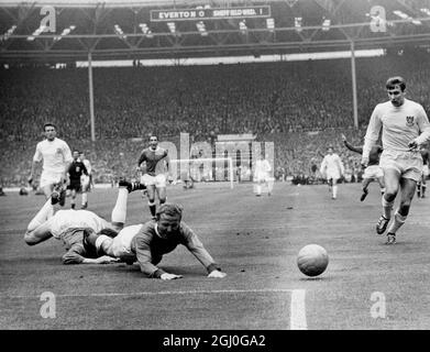 1966 FA Cup Final Everton v Sheffield Wednesday. Everton centre-forward, Alex Young (nearest camera) and Sheffield Wednesday goalkeeper, Ron Springett both dive and miss the ball. On the right is Sheffield's right-back, W. Smith. 14th May 1966 Stock Photo