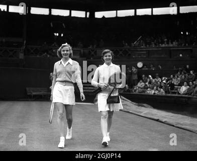 Mrs A J Mottram of Great Britain (left) and Mrs W du Pont (right) of the United States , walk out onto the centre court of the All England Club for their match in the first round of the Ladies ' Single Tennis Championship at Wimbledon in London . Mrs du Pont won the game : 6 - 3 6 - 4 . 26th June 1951 Stock Photo