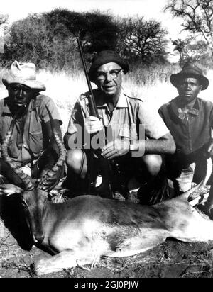 Dr G Howard Rothfuss with his tracker, his gunbearer, and a big male impala he brought down on a recent hunting trip. 15 December 1967 Stock Photo