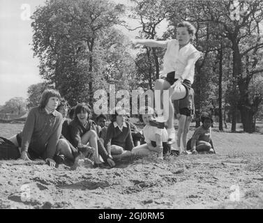 SCHOOLCHILDREN AT THE PLAYING FIELDS. Many lucky schoolchildren visit the London County Council's excellent 80 acres of sports ground at Morden, Surrey, for their Physical Education and games. PHOTOGRAPH SHOWS:- MAUREEN SMITH, aged 13, takes her turn at the long jump watched by other girls from the Parkside Secondary School, Brixton. 5 June 1962 Stock Photo