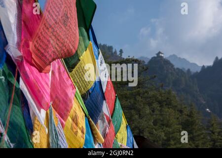 Bhutan, Paro. Colorful prayer flages in front of small outbuilding of the Tiger's Nest, sacred Himalayan Buddhist temple complex. Stock Photo