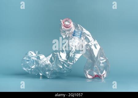 Composition of two used crushed plastic bottles on the blue background. Recycling concept. Stock Photo