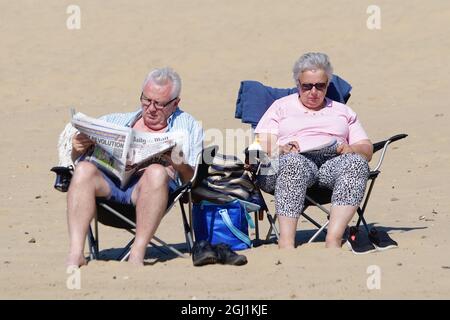 Camber, East Sussex, UK. 08 Sep, 2021. UK Weather: Visitors to Camber Sands in East Sussex enjoy the warm and sunny weather on the golden sandy beaches. An elderly couple sitting in deckchairs on the beach reading, the man is reading the Daily Mail newspaper. Photo Credit: Paul /Alamy Live News Stock Photo