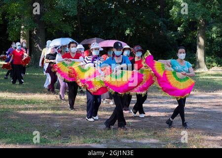 A group of women in a dance exercise class rehearse for a performance carrying flags with colorful fabrics. In a park in Flushing Queens, NYC. Stock Photo