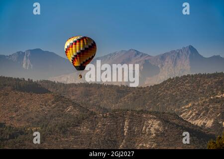USA, Colorado, Uncompahgre National Forest. Hot air balloon floats above mountain terrain. Stock Photo