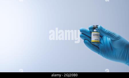 Doctor hands in blue latex gloves holding glass vial with medicine.  Vaccination and Medical concept. Stock Photo