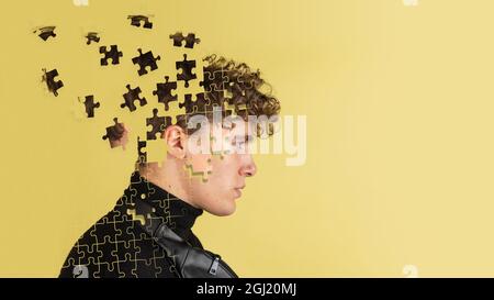 Artwork. Side view of young man's head made of flying pieces of puzzle, modern art collage. Concept of diversity, mental health, emotion, inner world Stock Photo