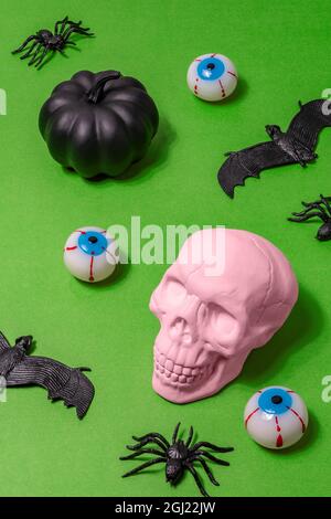 Halloween concept with pink skull, spiders, bats and eyeballs. Minimal holiday background. Stock Photo