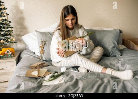 Cute girl making handmade advent calendar at home on the bed. Stock Photo