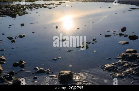 Early morning sun reflected in a pool of water on a beach Stock Photo