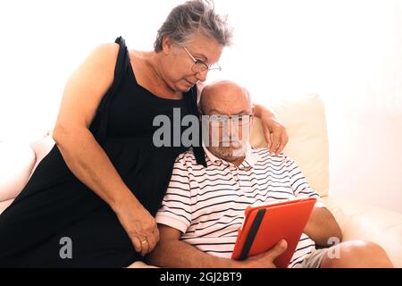 Senior couple using a digital tablet with a surprised face with a white background and copyspace Stock Photo