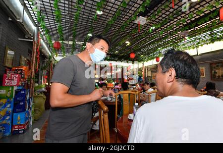 (210908) -- TIANJIN, Sept. 8, 2021 (Xinhua) -- Li Chao (L) serves a customer at his farmyard in Xiaoxinmatou Village of Baodi District in Tianjin, north China, Sept. 2, 2021. Li Chao is a post-90s born in Xiaoxinmatou Village in Baodi District. Located by the Chaobai River, the village used to witness an outflow of young people, as villagers made a living by traditional fishing and farming with low income. Like his young fellows, Li chose to be a migrant worker in the city for higher income. Waiter, chef, assembly line worker, security guard and salesman.the diligent man tried his hand Stock Photo