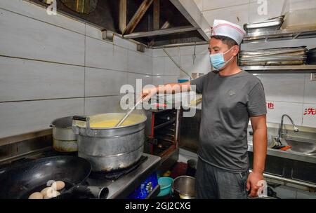 (210908) -- TIANJIN, Sept. 8, 2021 (Xinhua) -- Li Chao prepares breakfast for customers in Xiaoxinmatou Village of Baodi District in Tianjin, north China, Sept. 3, 2021. Li Chao is a post-90s born in Xiaoxinmatou Village in Baodi District. Located by the Chaobai River, the village used to witness an outflow of young people, as villagers made a living by traditional fishing and farming with low income. Like his young fellows, Li chose to be a migrant worker in the city for higher income. Waiter, chef, assembly line worker, security guard and salesman.the diligent man tried his hand at a Stock Photo