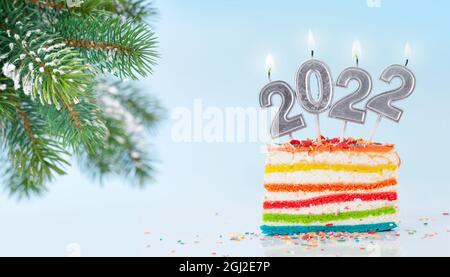 Christmas cake with number 2022 burning candles on a blue background and fir tree branch Stock Photo