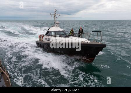 Pilot boat Barracuda greets ship entering Poole Harbour, Poole, Dorset UK in August Stock Photo