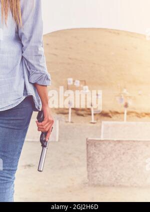 Gun in the hands of a girl, close-up arms. Stock Photo