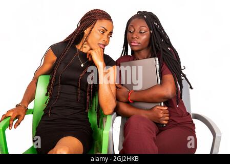 two young African students sitting on chairs talking together with a laptop Stock Photo