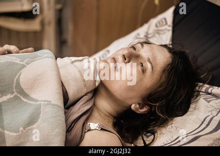 A woman who gave birth to a newborn baby boy. Laying the child out on the mother chest immediately after childbirth Stock Photo