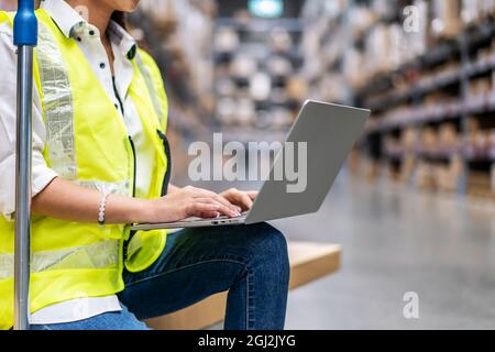 Young female warehouse workers working on laptop in a large warehouse Stock Photo